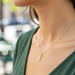 Cuello de modelo usando una cadena con un dije en forma de clave de sol en oro amarillo de 18 quilates de Joyería Caracas.