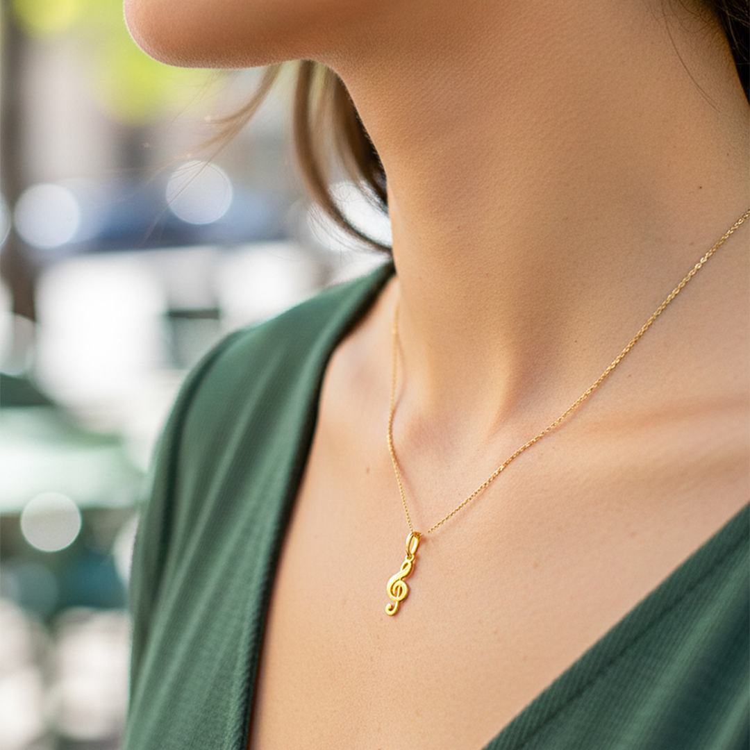 Cuello de modelo usando una cadena con un dije en forma de clave de sol en oro amarillo de 18 quilates de Joyería Caracas.