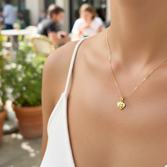 Cuello de modelo usando una cadena con un dije en forma de corazón con angelito diamantado en oro amarillo de 18 quilates de Joyería Caracas.