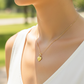 Cuello de modelo usando una cadena con un dije en forma de corazón con angelito en oro amarillo de 18 quilates de Joyería Caracas.