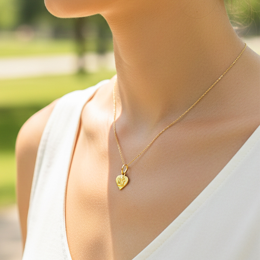 Cuello de modelo usando una cadena con un dije en forma de corazón con angelito en oro amarillo de 18 quilates de Joyería Caracas.