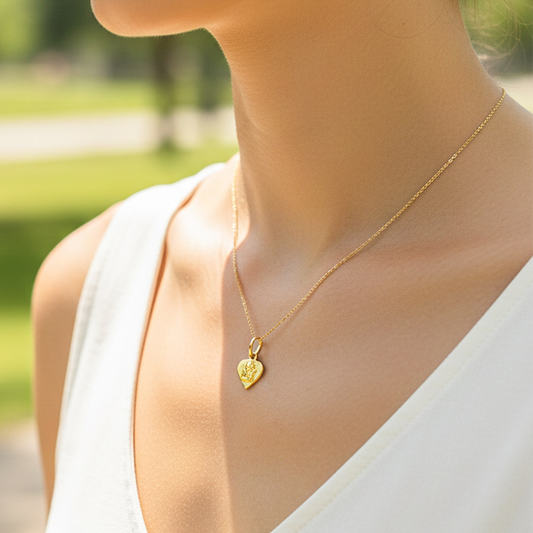 Cuello de modelo usando una cadena con un dije en forma de corazón con angelito en oro amarillo de 18 quilates de Joyería Caracas.
