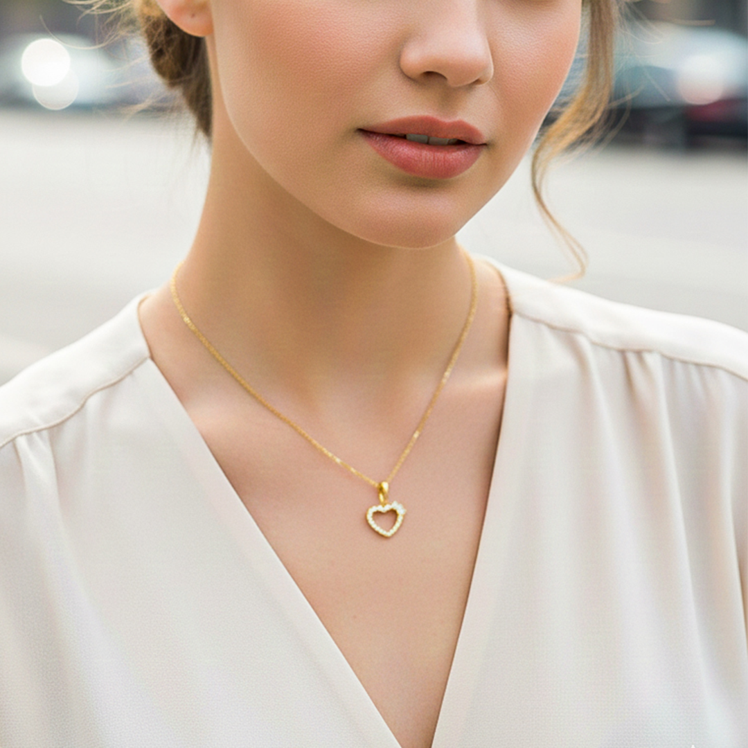 Cuello de modelo usando una cadena con un dije en forma de corazón en oro amarillo de 18 quilates con cristales de Joyería Caracas.