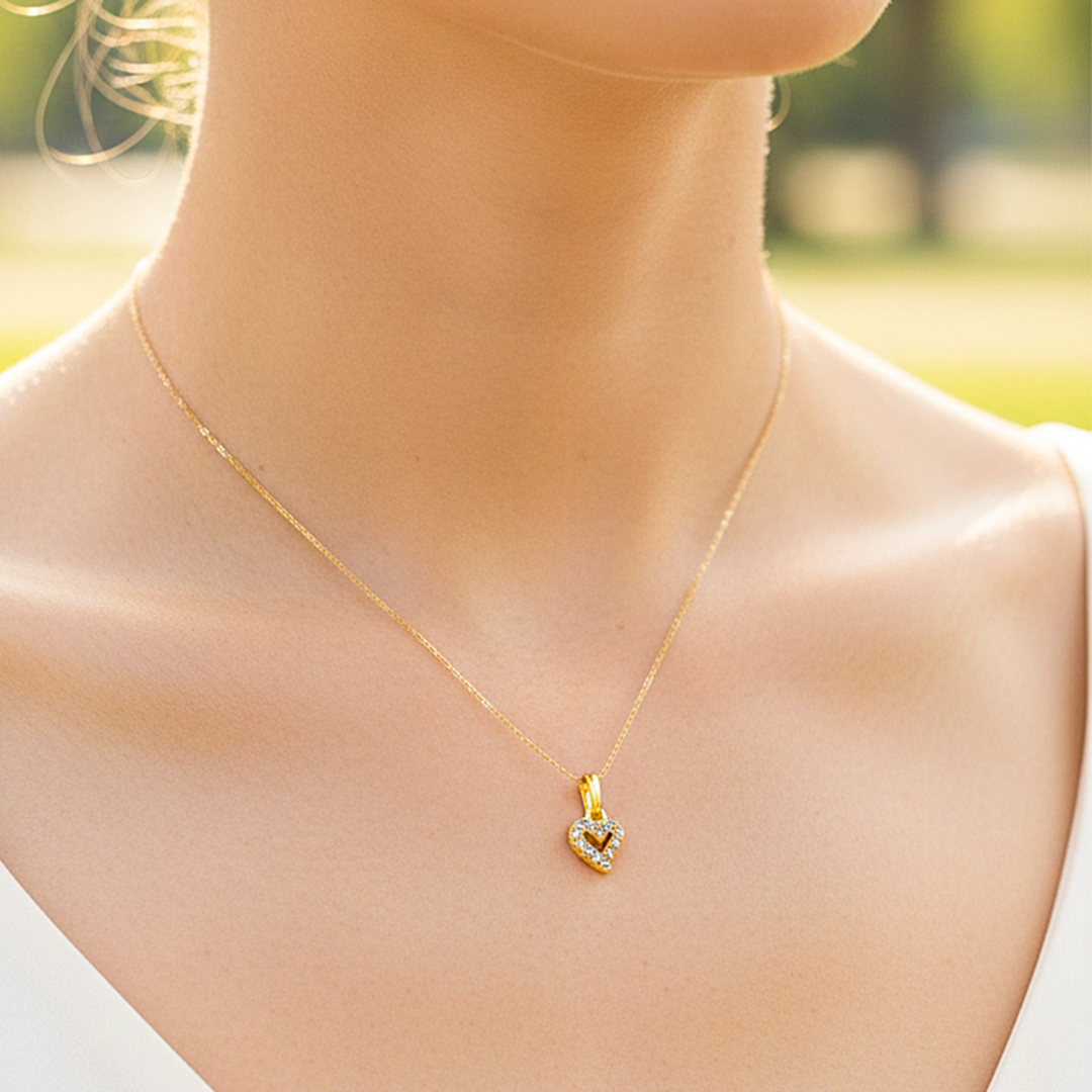 Cuello de modelo usando una cadena con un dije en forma de corazón en oro amarillo de 18 quilates con cristales de Joyería Caracas.