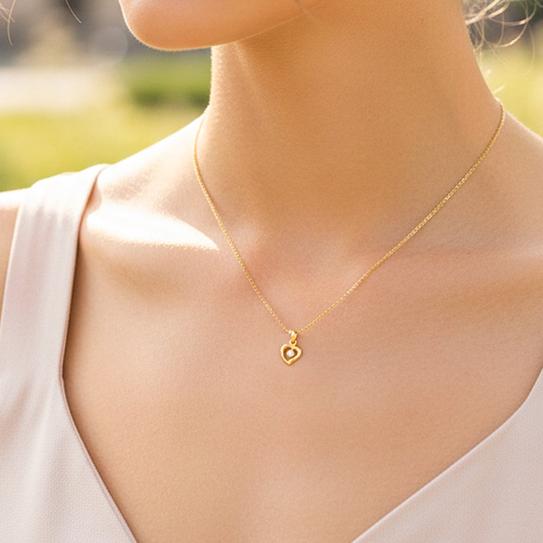 Cuello de modelo usando una cadena con un dije en forma de corazón en oro amarillo de 18 quilates con cristal de Joyería Caracas.