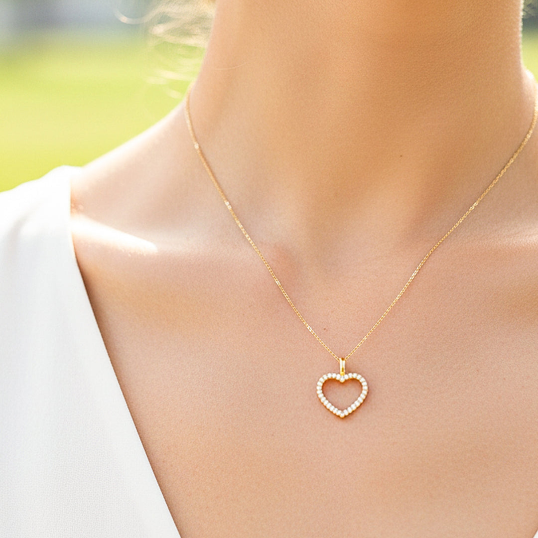 Cuello de modelo usando una cadena con un dije en forma de corazón en oro amarillo de 18 quilates con cristales de Joyería Caracas.