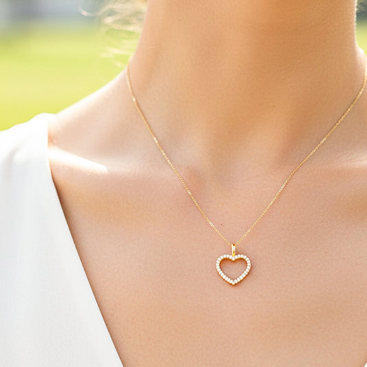 Cuello de modelo usando una cadena con un dije en forma de corazón en oro amarillo de 18 quilates con cristales de Joyería Caracas.