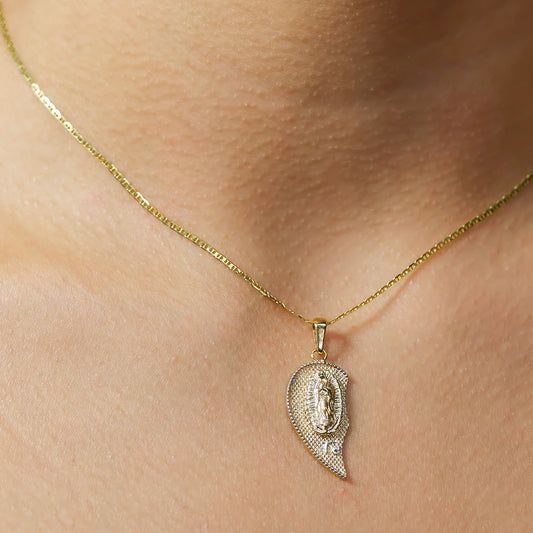 Cuello de mujer usando un dije de medio corazón de la Virgen de Guadalupe en oro amarillo de 18 quilates de Joyería Caracas. 