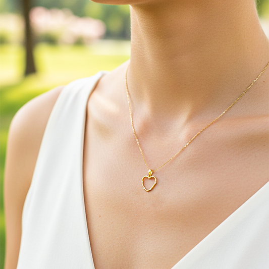 Cuello de modelo usando una cadena con un dije en forma de corazón embastado en oro amarillo de 18 quilates con cristales de Joyería Caracas.