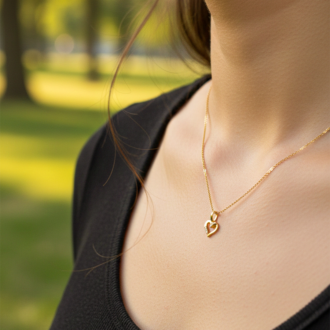 Cuello de modelo usando una cadena con un dije en forma de corazón en oro amarillo de 18 quilates con cristales de Joyería Caracas.