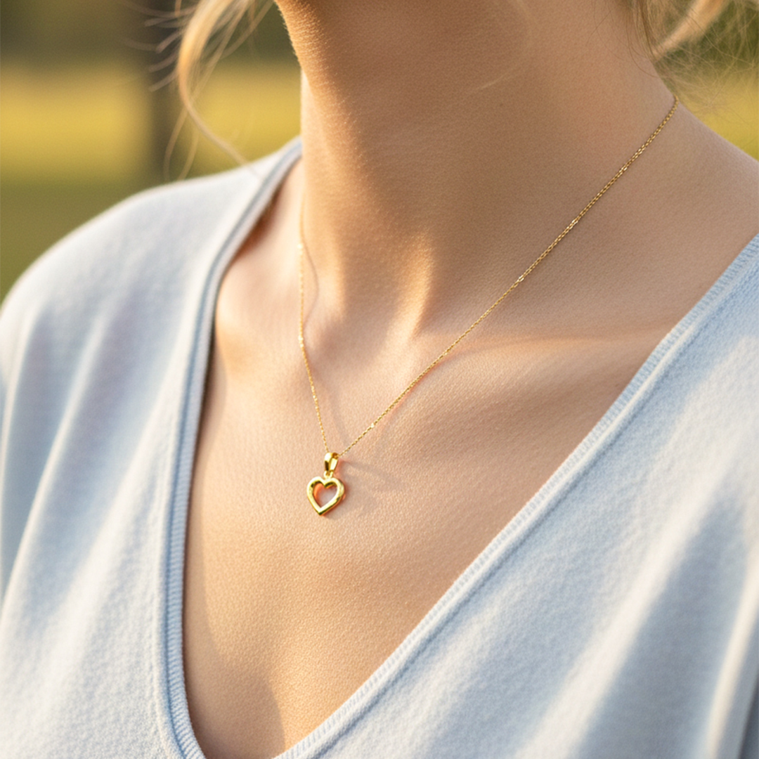 Cuello de modelo usando una cadena con un dije en forma de la silueta de corazón en oro amarillo de 18 quilates de Joyería Caracas.