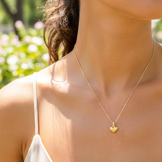 Cuello de modelo usando una cadena con un dije en forma de corazón soplado en oro amarillo de 18 quilates de Joyería Caracas.