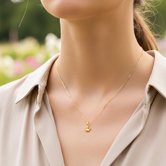 Cuello de modelo usando una cadena con un dije en forma de corona en oro amarillo de 18 quilates de Joyería Caracas.