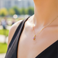Cuello de modelo usando una cadena con un dije en forma de corona en oro amarillo de 18 quilates con cristales blancos y rojo de Joyería Caracas.