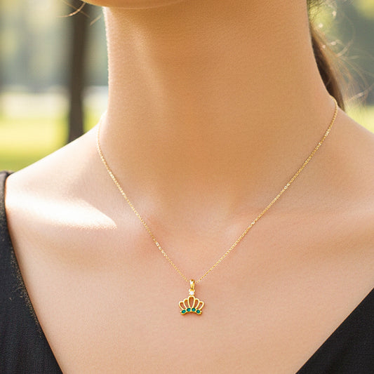 Cuello de modelo usando una cadena con un dije en forma de corona en oro amarillo de 18 quilates con cristales verdes de Joyería Caracas.