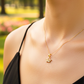 Cuello de modelo usando una cadena con un dije en forma de corona inglesa en oro amarillo de 18 quilates con cristales de Joyería Caracas.