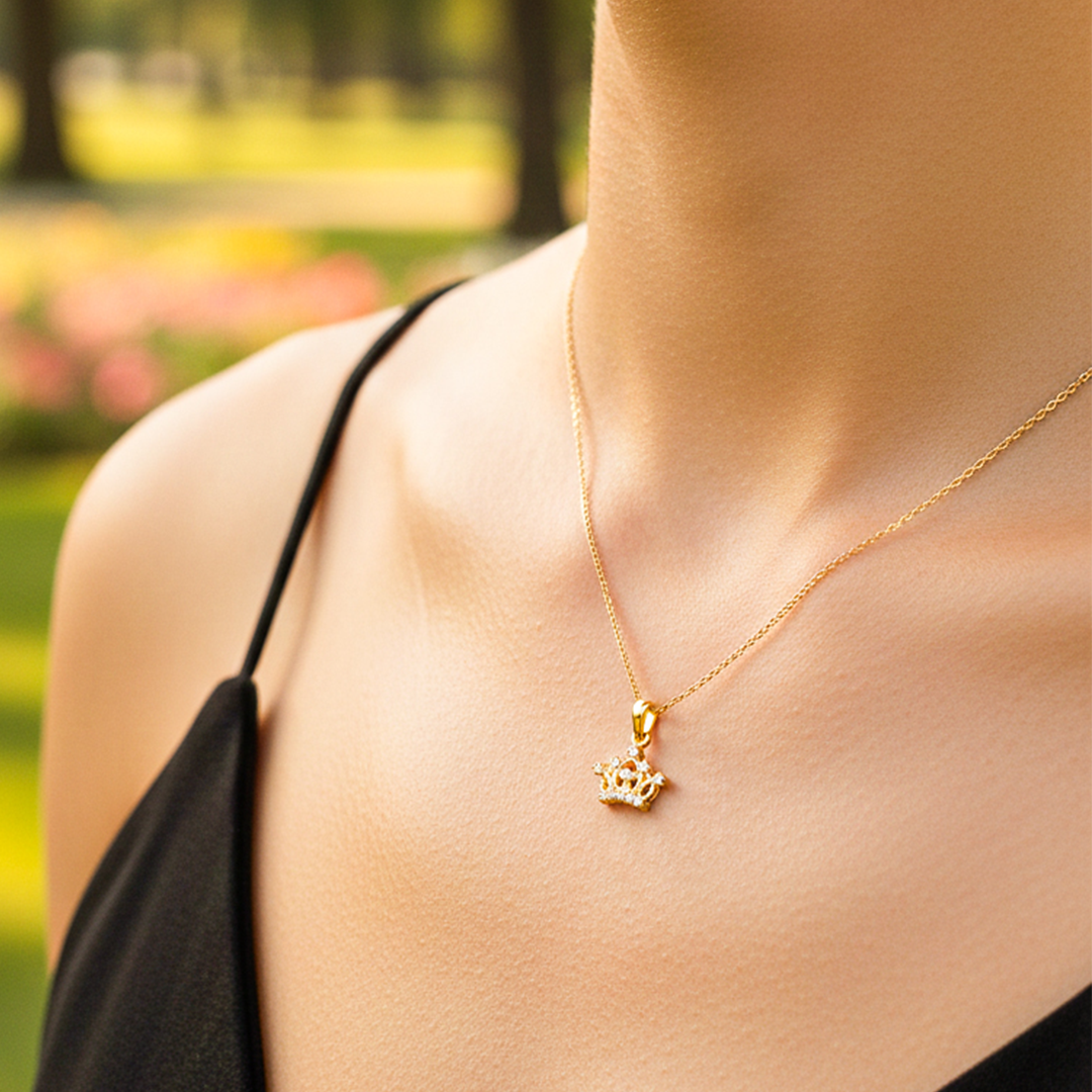 Cuello de modelo usando una cadena con un dije en forma de corona inglesa en oro amarillo de 18 quilates con cristales de Joyería Caracas.