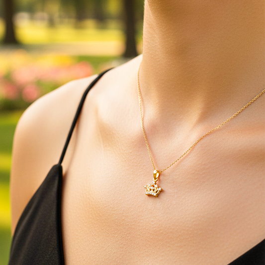 Cuello de modelo usando una cadena con un dije en forma de corona inglesa en oro amarillo de 18 quilates con cristales de Joyería Caracas.