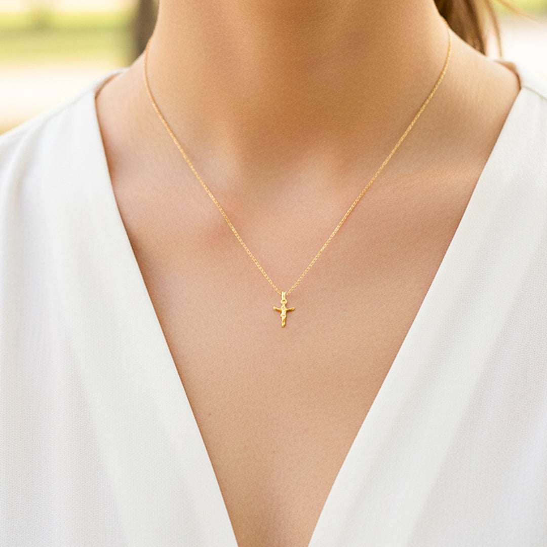 Cuello de modelo usando una cadena con un dije en forma de Cristo en oro amarillo de 18 quilates de Joyería Caracas.