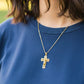 Cuello de modelo usando una cadena con un dije en forma de cruz de malla en oro amarillo de 18 quilates de Joyería Caracas.