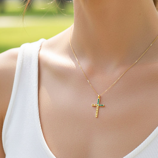 Cuello de modelo usando una cadena con un dije en forma de cruz oro amarillo de 18 quilates con Esmeraldas de Joyería Caracas.