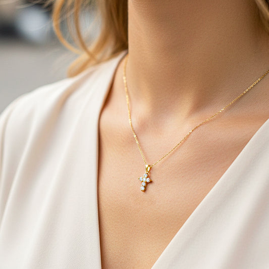 Cuello de modelo usando una cadena con un dije en forma de cruz en oro amarillo de 18 quilates con cristales de Joyería Caracas.