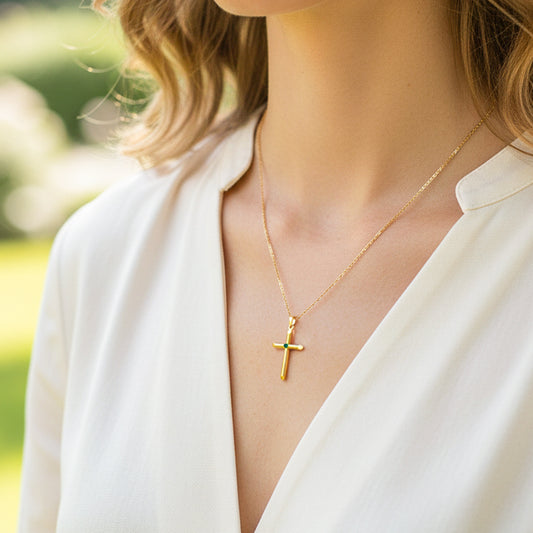 Cuello de modelo usando una cadena con un dije de cruz en oro amarillo de 18 quilates con Esmeralda de Joyería Caracas.