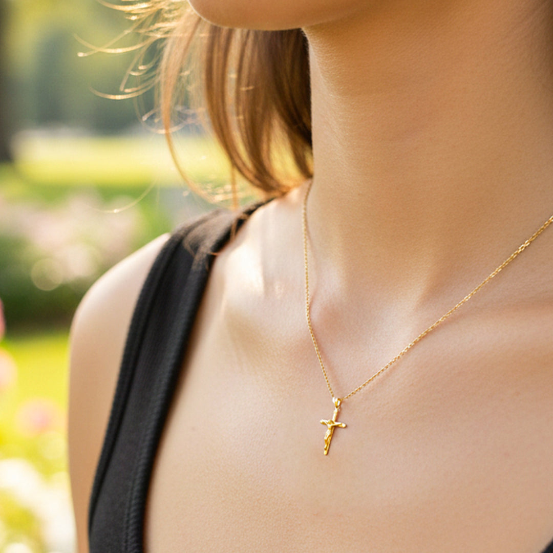 Cuello de modelo usando una cadena con dije en forma de cruz con cristo en oro amarillo de 18 quilates de Joyería Caracas. 