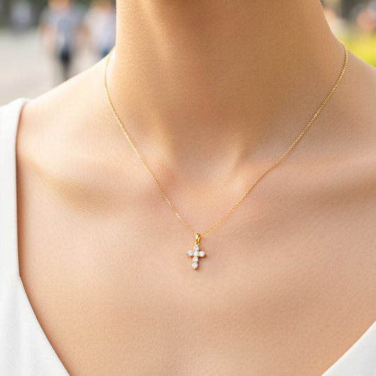 Cuello de modelo usando una cadena con un dije en forma de cruz en oro amarillo de 18 quilates con cristales de Joyería Caracas.