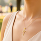 Cuello de modelo usando una cadena con un dije en forma de cruz simétrica en oro amarillo de 18 quilates de Joyería Caracas.