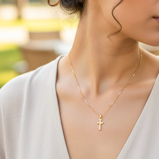 Cuello de modelo usando una cadena con un dije en forma de cruz en oro amarillo de 18 quilates con cristales de Joyería Caracas.