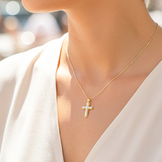 Cuello de modelo usando una cadena con un dije en forma de Cruz en círculos en oro amarillo y blanco de 18 quilates con cristales de Joyería Caracas.