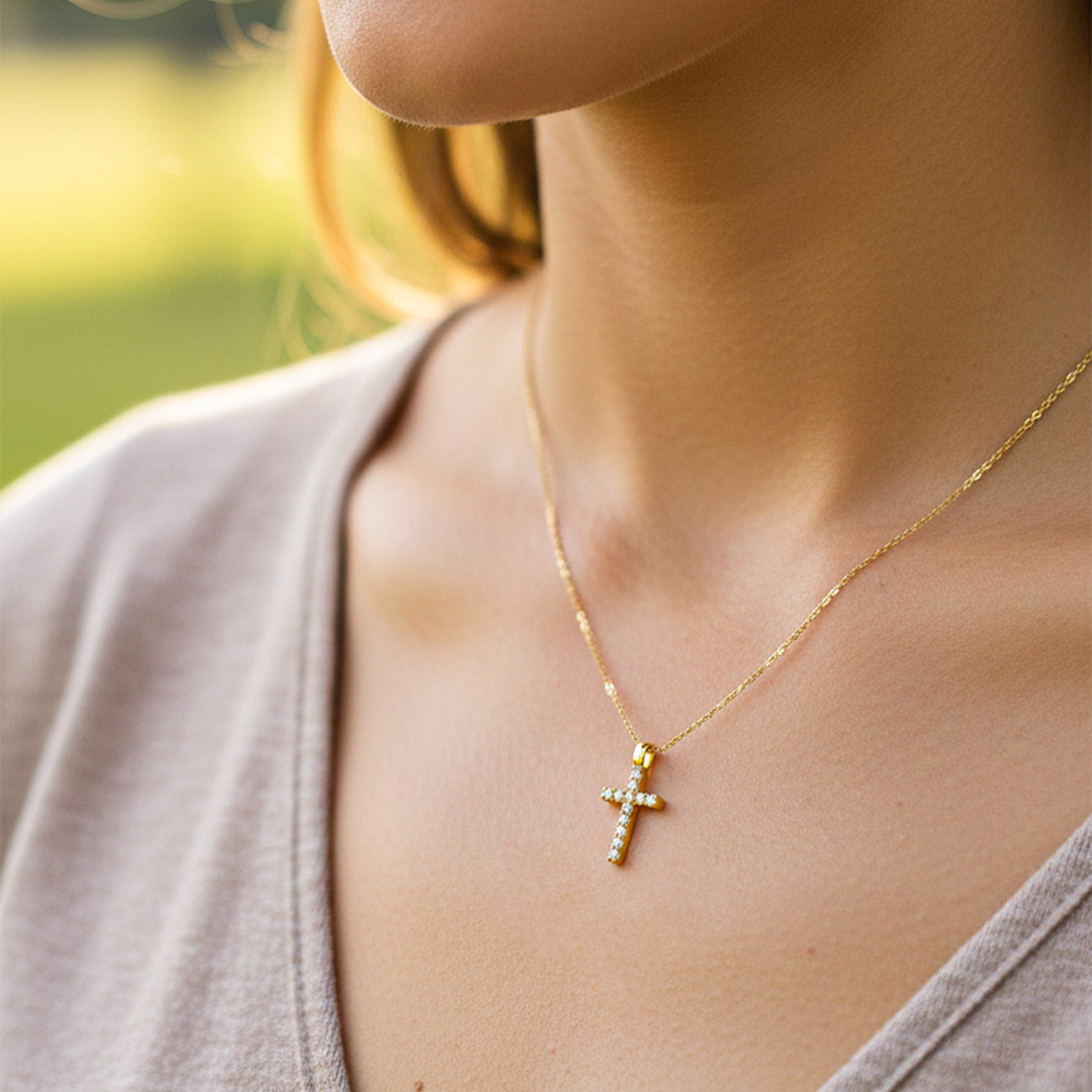 Cuello de modelo usando una cadena con un dije en forma de cruz en oro amarillo de 18 quilates con cristales de Joyería Caracas.