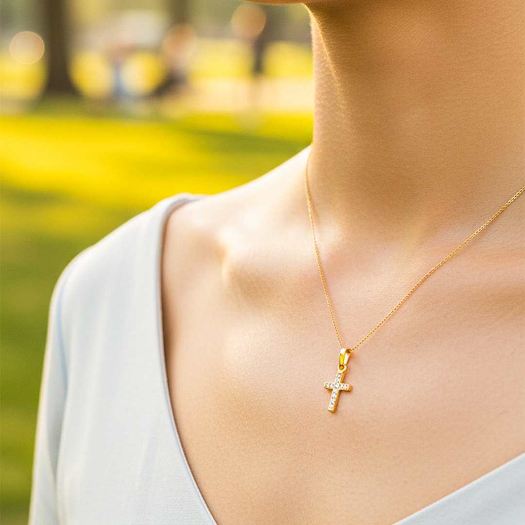 Cuello de modelo usando una cadena con un dije en forma de cruz en oro amarillo de 18 quilates con cristales de Joyería Caracas.