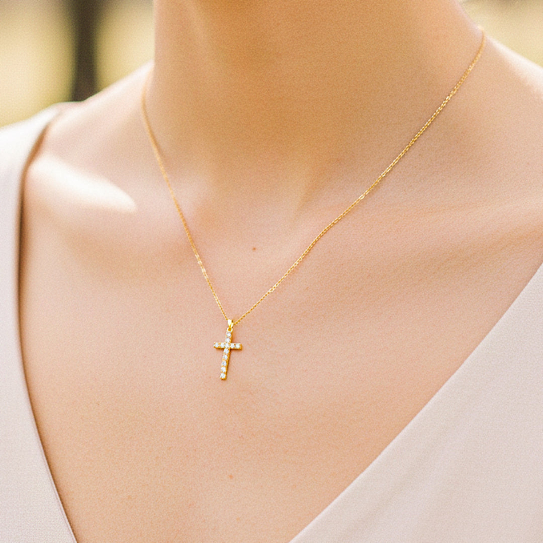 Cuello de modelo usando una cadena con un dije en forma de Cruz en oro amarillo de 18 quilates con cristales de Joyería Caracas.