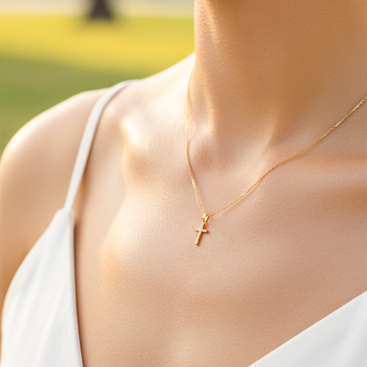 Cuello de modelo usando una cadena con un dije en forma de cruz en oro amarillo de 18 quilates con cristales de Joyería Caracas.