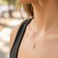 Cuello de modelo usando una cadena con un dije en forma de cruz en oro amarillo de 18 quilates con cristales de Joyería Caracas.