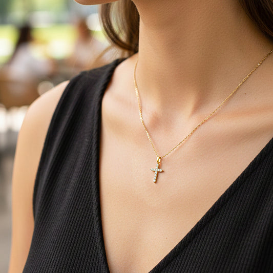 Cuello de modelo usando una cadena con un dije cruz en oro amarillo de 18 quilates con cristales de Joyería Caracas.