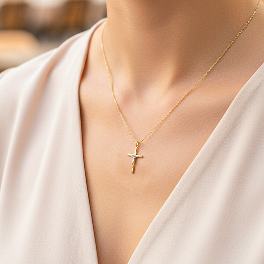 Cuello de modelo usando una cadena con un dije en forma de Cruz con Cristo en oro amarillo y blanco de 18 quilates de Joyería Caracas.