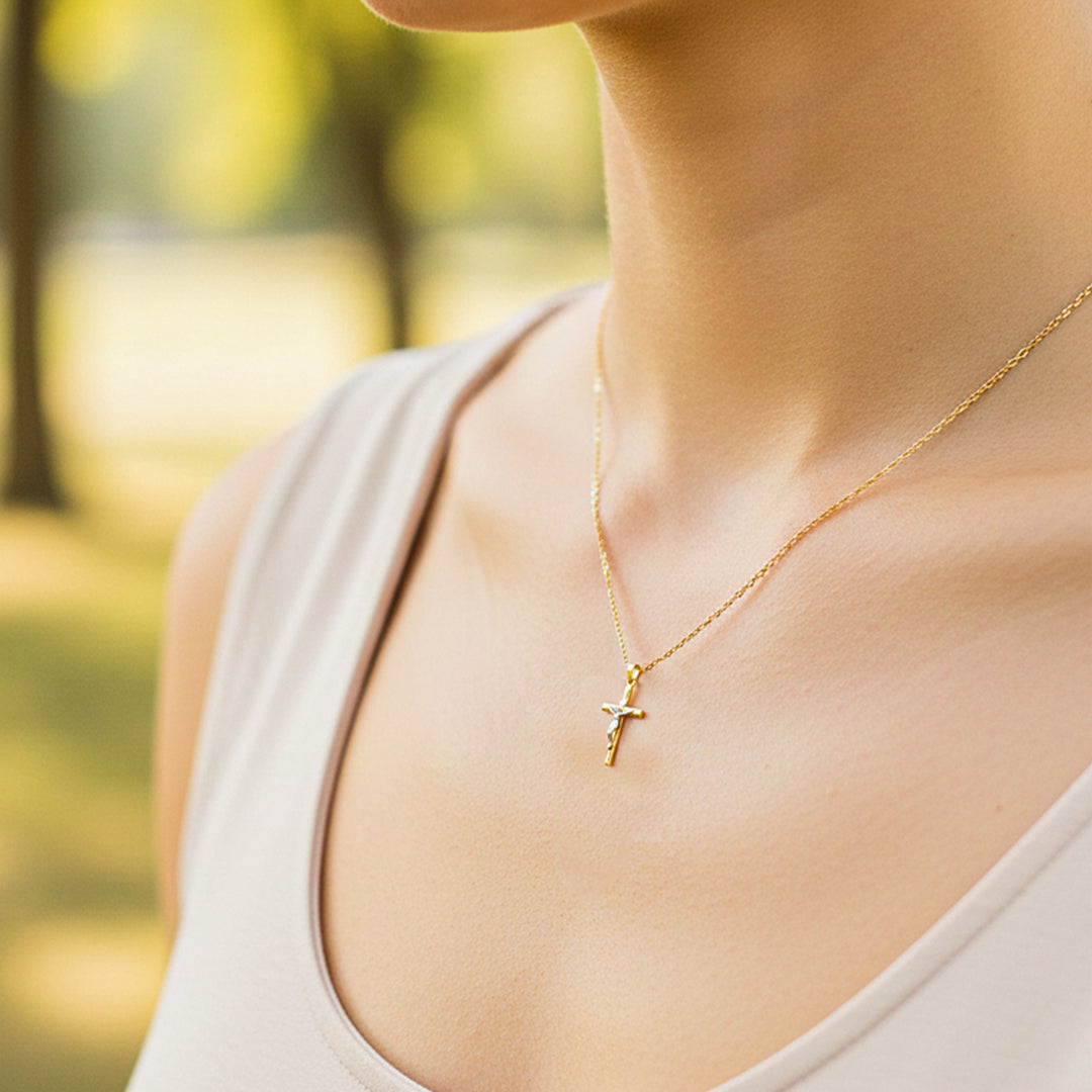 Cuello de modelo usando una cadena con un dije en forma de Cruz con Cristo en oro amarillo y blanco de 18 quilates de Joyería Caracas.