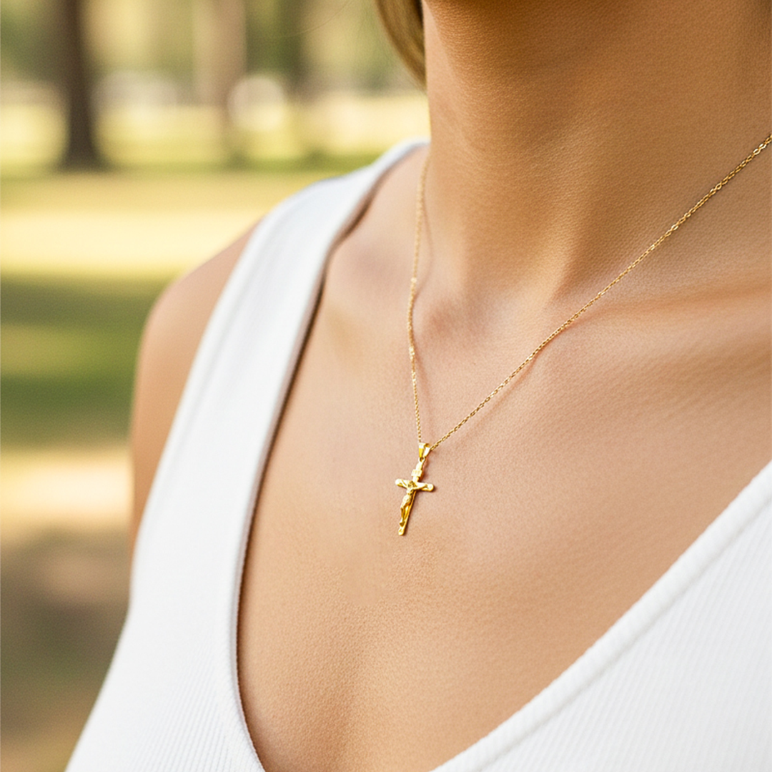 Cuello de modelo usando una cadena con un dije en forma de Cruz con cristo en tubo en oro amarillo de 18 quilates de Joyería Caracas.