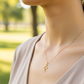 Cuello de modelo usando una cadena con un dije en forma del croquis de una cruz en oro amarillo de 18 quilates de Joyería Caracas.