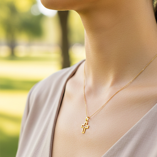 Cuello de modelo usando una cadena con un dije en forma del croquis de una cruz en oro amarillo de 18 quilates de Joyería Caracas.