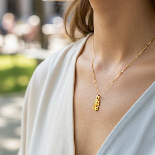Cuello de modelo usando una cadena con un dije con forma de Cruz de Caravaca en oro amarillo de 18 quilates de Joyería Caracas.