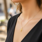 Cuello de modelo usando una cadena con un dije en forma de Cruz de los Milagros en oro amarillo de 18 quilates de Joyería Caracas.