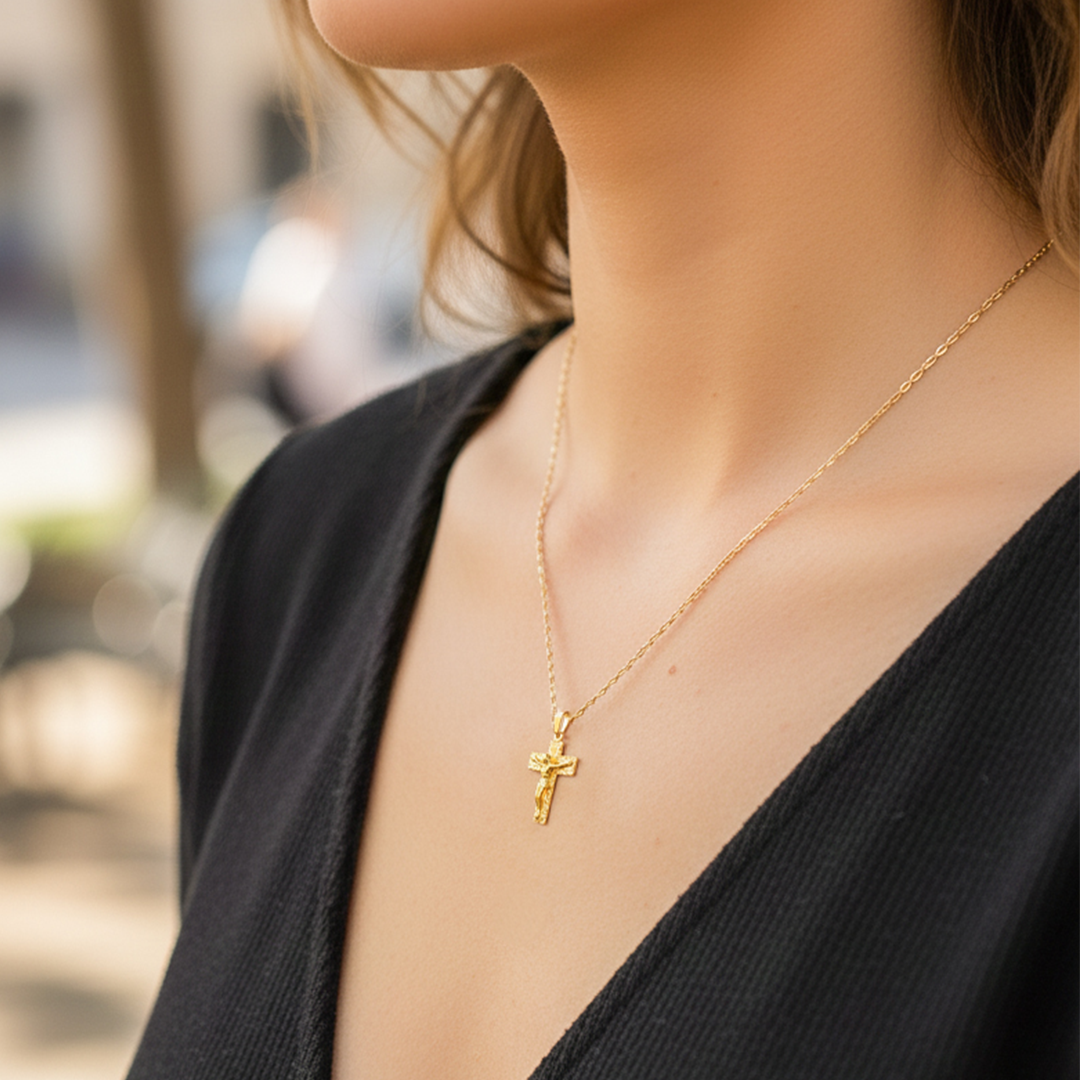 Cuello de modelo usando una cadena con un dije en forma de Cruz de los Milagros en oro amarillo de 18 quilates de Joyería Caracas.
