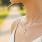 Cuello de modelo usando una cadena con un dije en forma de cruz diamantada mini en oro amarillo de 18 quilates de Joyería Caracas.