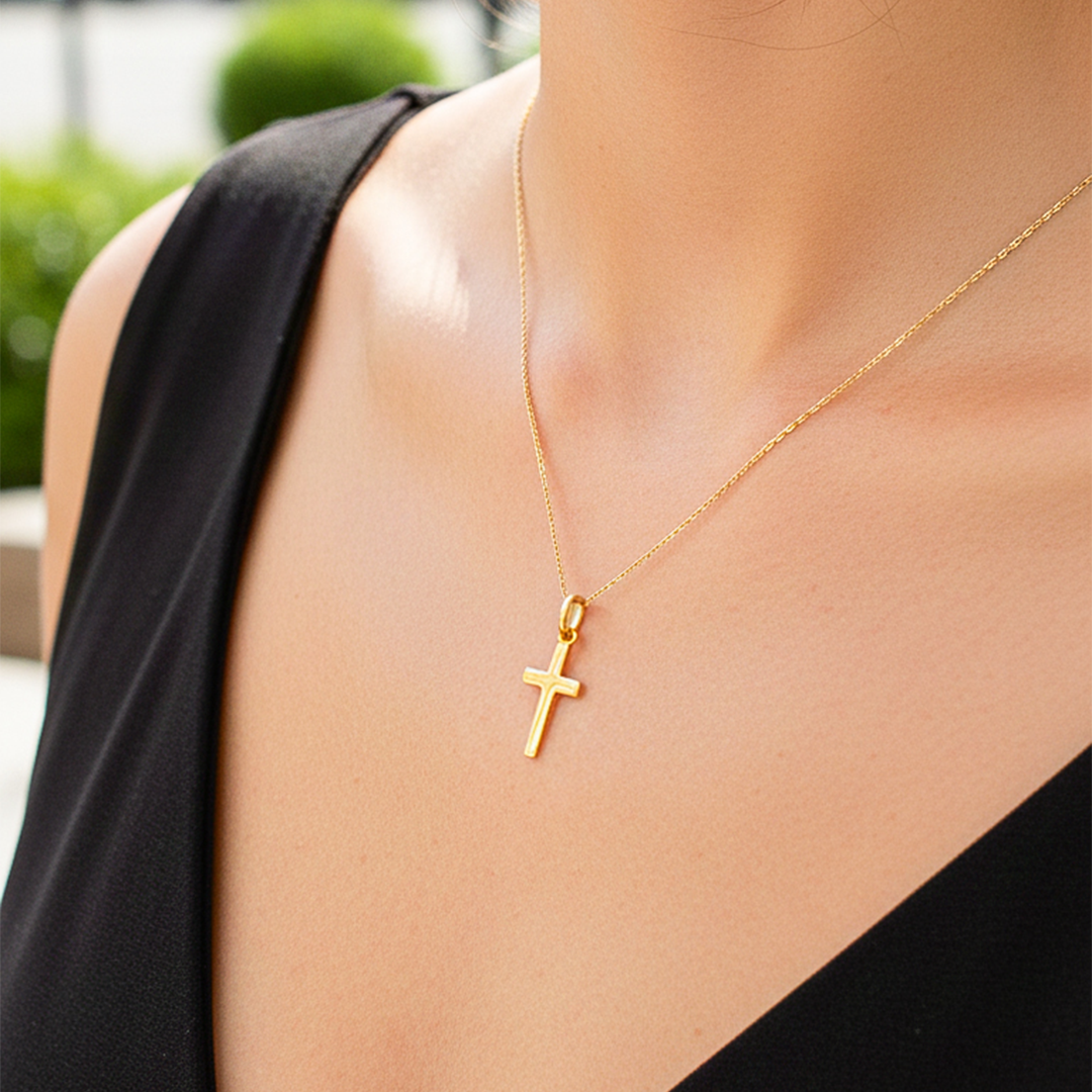 Cuello de modelo usando una cadena con un dije en forma de cruz en oro amarillo de 18 quilates de Joyería Caracas.