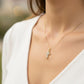 Cuello de modelo usando una cadena con un dije en forma de cruz mini de círculos en oro amarillo y blanco de 18 quilates de Joyería Caracas.