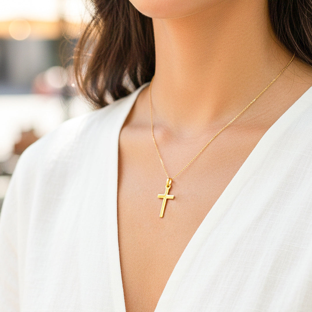 Cuello de modelo usando una cadena con un dije en forma de cruz tubo en oro amarillo de 18 quilates de Joyería Caracas.